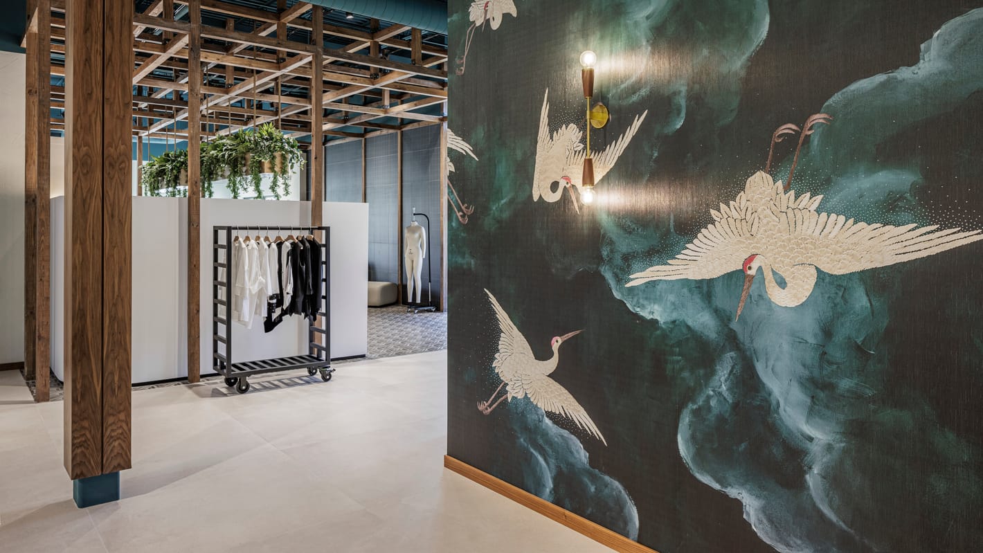 Crane mural feature wall beside rolling display racks under a timber ceiling